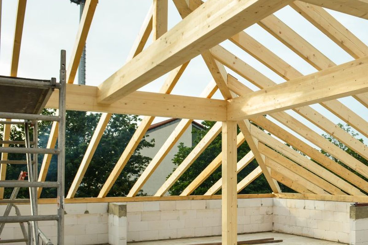 Exposed timber roof trusses standing over a new blockwork wall, before the roof sheeting goes on