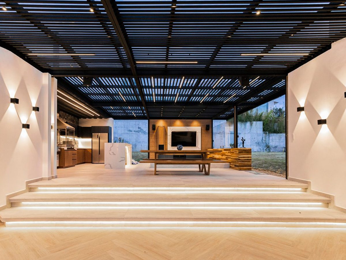 An open plan living and kitchen space opening to a garden through full height sliding glass
